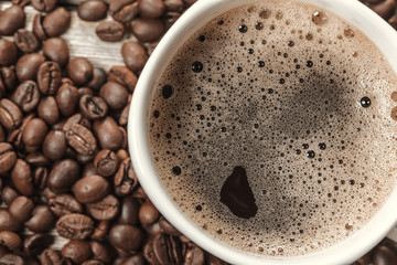 Cup of coffee and beans on wooden background