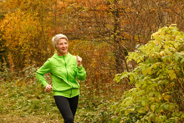 Senior woman doing sport outdoors,exercising on a forest road in the autumn .Pensioner woman sport