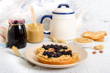 Toast with peanut butter and berry jam on a plate, tea. Nutritious breakfast.