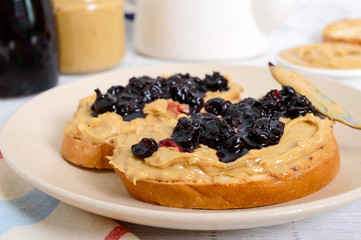Toast with peanut butter and berry jam on a plate, tea. Nutritious breakfast.
