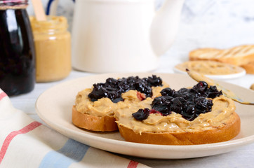 Toast with peanut butter and berry jam on a plate, tea. Nutritious breakfast.