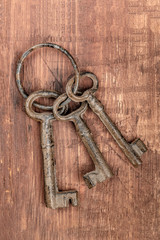 A top shot of vintage keys on a ring, on a dark wooden background with a place for text