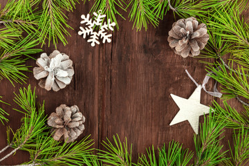 Christmas background with fir tree branches, cones, snow and xmas decorations on a dark wooden texture with a place for text