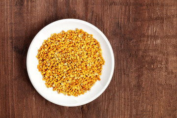 Healthy organic food. A top shot of pollen in a white plate on a dark wooden background with copy space