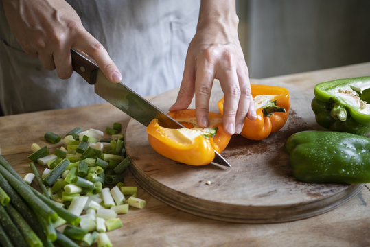 Cook slicing bell peppers on a cutting board
