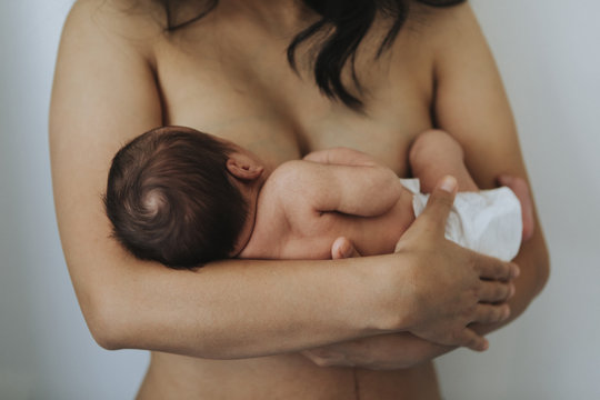 Naked mother holding her infant baby