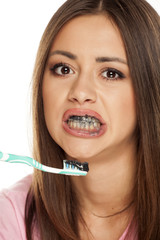 young woman brushing her teeth with black active charcoal toothpaste on white background
