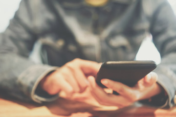 Woman hand using smartphone and laptop with cafe shop sunlight  shade to object beautiful background.