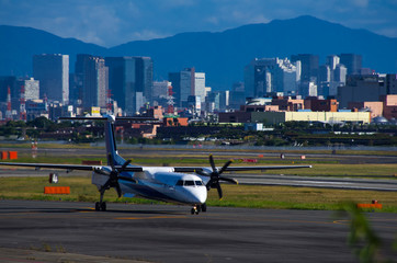 大阪の街並みと伊丹空港のプロペラ機
