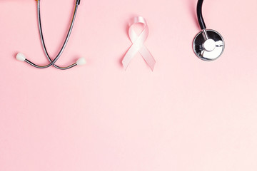 Pink ribbon and stethoscope on pink background wiyh copy space. Breast cancer awareness symbol.