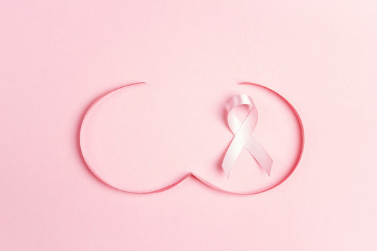 Pink ribbon with breast shape symbol on pink background.  Breast cancer awareness symbol. O
