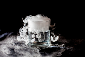 Glass with white smoke at dark background