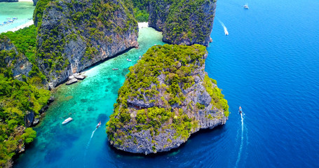 Aerial Overhead View of Lush Tropical Cove With Visible Coral Reef in Turquoise Water and Multiple Boats Moving Around Islands - Loh Samah Bay, Thailand
