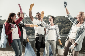 Cheerful volunteers. Team of active responsible volunteers feeling cheerful and inspired while...