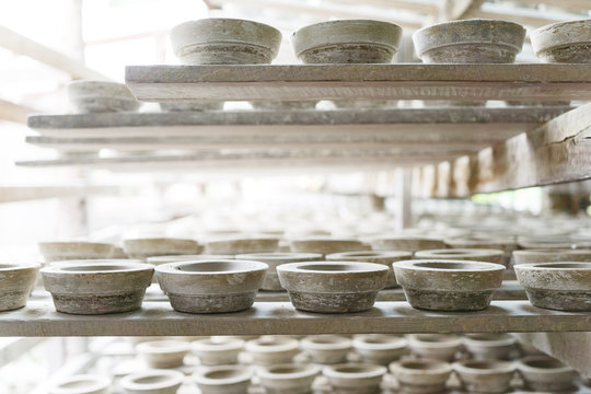 Handmade white clay pots dry on wooden planks. Workshop, manufactory interior