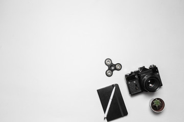 Minimal composition with vintage retro camera, diary with pen and fidget spinner on white desk....