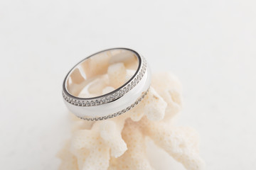 Obraz na płótnie Canvas Silver wedding ring with diamonds on white background with cora