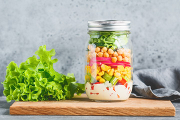 Fototapeta na wymiar Single jar with layering vegan salad for healthy lunch. The concept of fitness and vegetarian food.