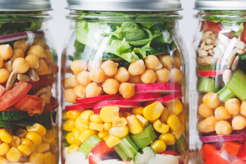 Three glass jars with layering various vegan salads for healthy lunch. Extrem close up. The concept of fitness and vegetarian food.
