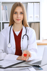 Female doctor with stethoscope holding heart in her arms. Healthcare and cardiology concept  in medicine