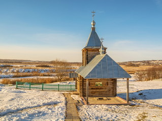 Winter landscape with a log chapel over a holy source