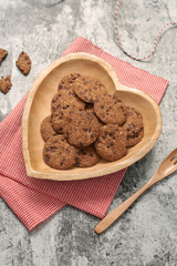 Chocolate chip cookies on heart-shape plate on grey stone background