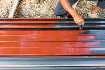 A Worker painting rustproof on steel poles for construction.