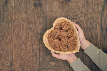 Plate of cookies in male hands on dark old wooden background top view