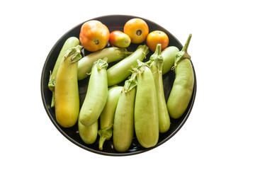 Green long eggplants and red tomatoes in black plate