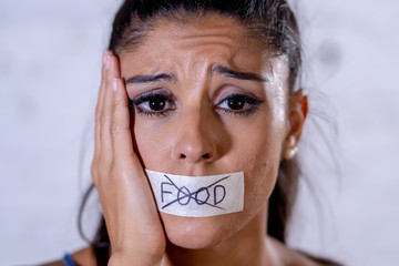 Close up face of sad beautiful woman with taped mouth text no food written
