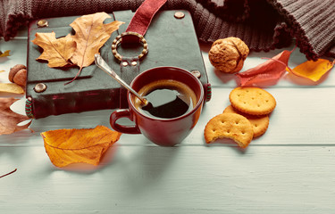 Cup coffee with book in leather binding autumn dry leaf and warm