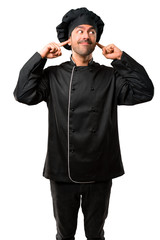 Chef man In black uniform covering both ears with hands on isolated white background