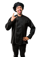 Chef man In black uniform showing tongue at the camera having funny look and taking out the horns on isolated white background