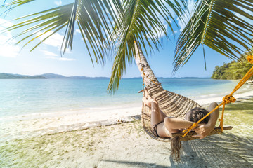 Summer vacations concept, Woman in swimsuit is relaxing in a hammock on a tropical beach El Nido on...