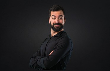 Obraz premium Handsome man with beard with his arms crossed on black background