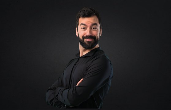 Handsome man with beard with his arms crossed on black background