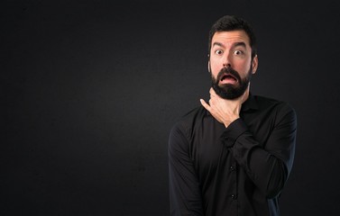 Handsome man with beard drowning himself on black background