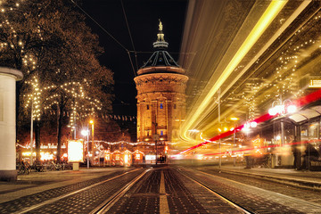 Fototapeta na wymiar Time Exposure train traffic light night Mannheim street public transport christmas holiday shopping water tower people