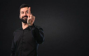 Handsome man with beard touching on transparent screen on black background