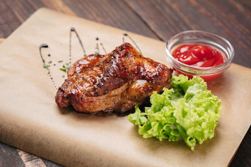 Grilled chicken with ketchup on dark wooden background