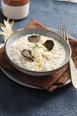 Risotto with black truffle and parmesan cheese in blue plate on rustic linen tablecloth, Copyspace.