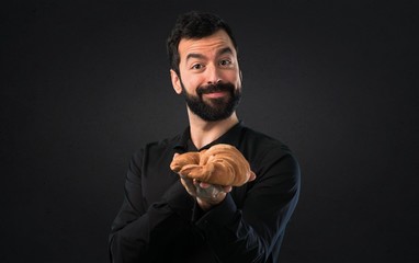 Handsome man with beard with pastry on black background