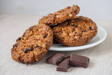 Chocolate chip cookies on white background. Stacked chocolate chip cookies on brown napkin. Freshly baked. Concept for a tasty snack. Sweet dessert. Selective focus. Close up.