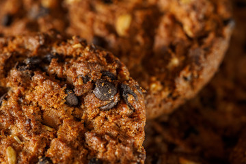 Chocolate chip cookies on rustic dark black background. Stacked chocolate chip cookies on brown napkin. Symbolic image with place for text. Freshly baked. Concept for a tasty snack. Sweet dessert. 
