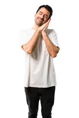 Fototapeta premium Young man with white shirt making sleep gesture. Adorable and sweet expression on isolated white background