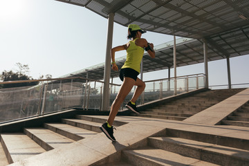 Young woman runner sportswoman running up city stairs jogging and running in urban training workout