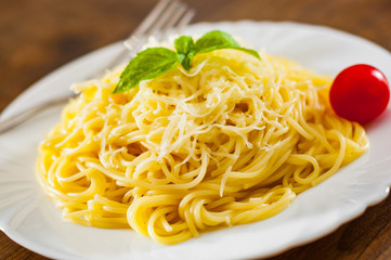 spaghetti pasta with grated cheese in white plate on wooden table