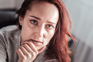 Personal problems. Portrait of a depressed thoughtful unhappy woman holding her chin and looking at you while having difficult time in life