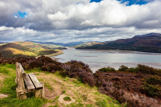 Wooden bench overlooking Mawddach river estuary at low tide with views to Snowdonia at low tide, near Barmouth, Wales