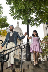 A couple of lovers dressed retro style walking down the stairs of a street of Montmartre, Paris, France
